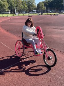 Woman on adapted pink bike in inclusive cycling session.